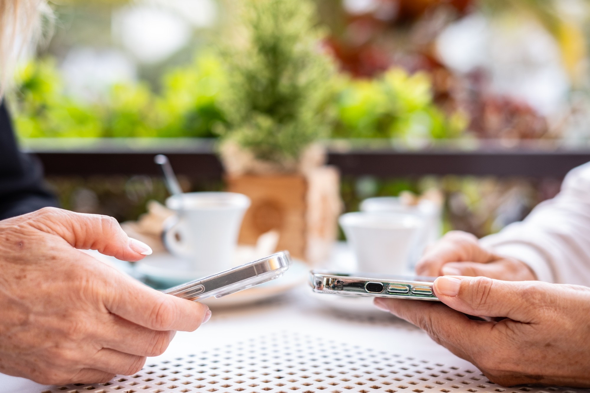 Close up view of two modern women's hands using apps and wireless technology to share files