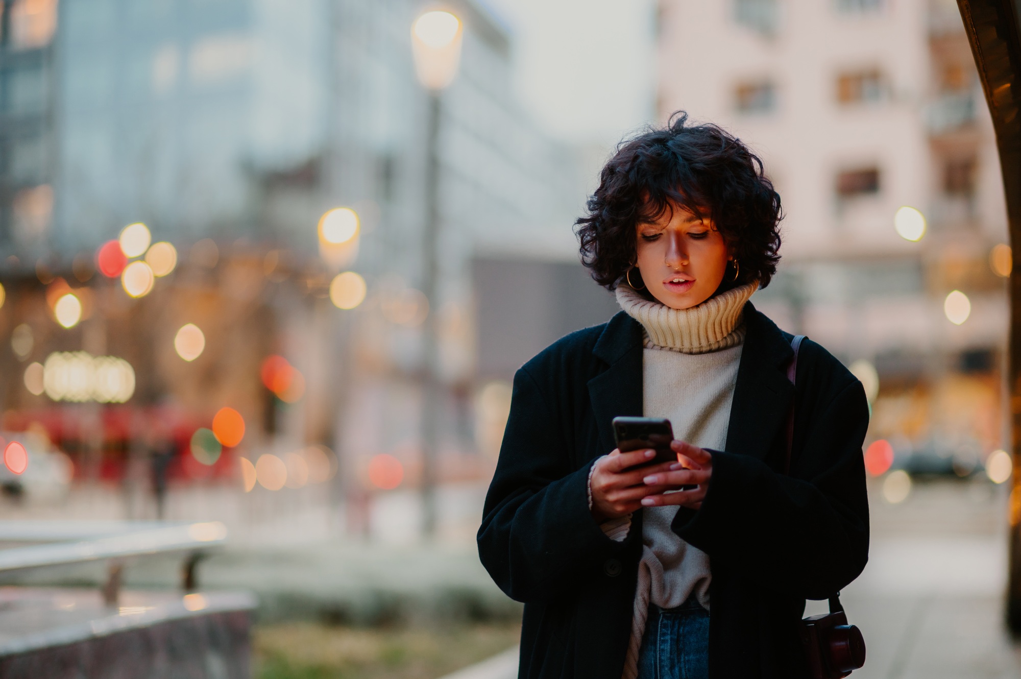Pretty woman walking down the streets while looking down to her smart phone.